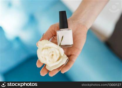 Woman holds nail varnish and a flower, beauty salon, manicure and pedicure procedure. Professional beautician service, female customer, toenail and fingernail care in spa studio. Woman holds nail varnish and a flower, beauty salon