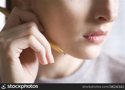 Woman holds pencil next to face