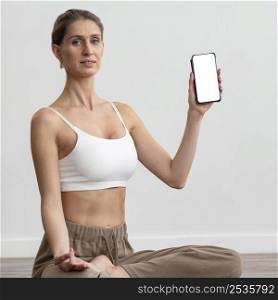 woman home doing yoga holding smartphone