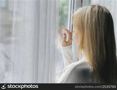 woman home during pandemic looking through window