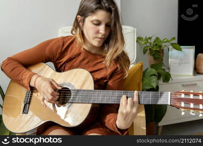 woman home playing guitar