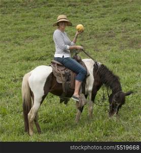 Woman horseback riding in a field, Finca El Cisne, Honduras