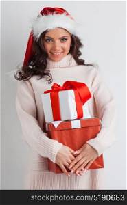 Woman hug Christmas gifts. Young woman in Santa hat hug her Christmas gifts