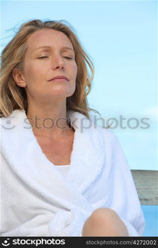 Woman in a bathrobe relaxing in the sunshine