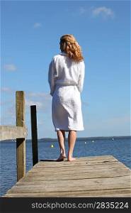 Woman in a bathrobe standing on a wooden pier