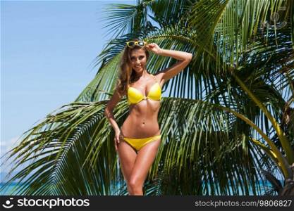 Woman in a bikini on beach over background of palm trees. Woman in bikini on beach