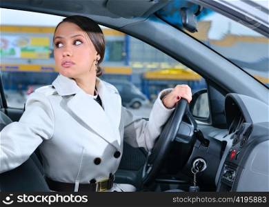 woman in a car is looking backwards trying to move back
