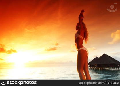 woman in a dress on a bridge home sea and the maldivian sunset on the background