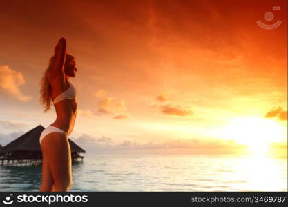 woman in a dress on a bridge home sea and the maldivian sunset on the background