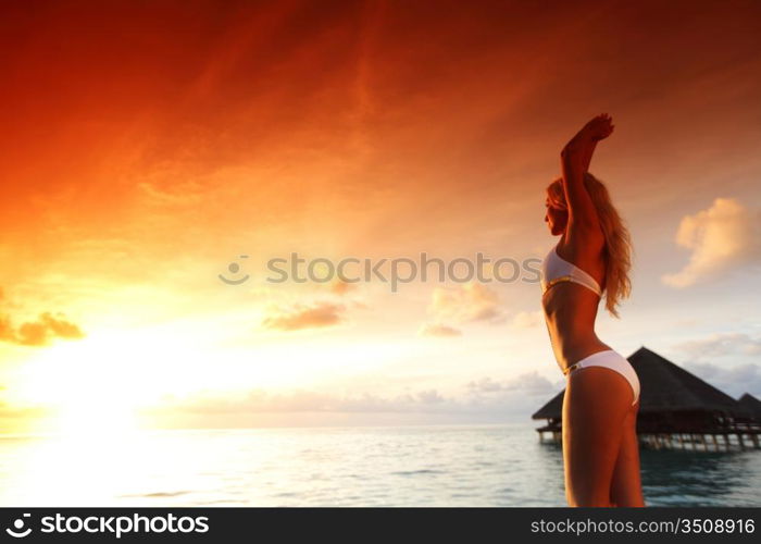 woman in a dress on a bridge home sea and the maldivian sunset on the background