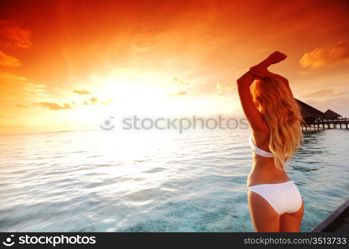 woman in a dress on a bridge home sea and the maldivian sunset on the background