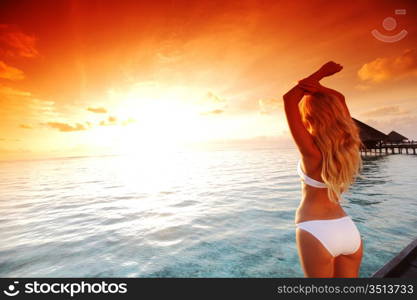 woman in a dress on a bridge home sea and the maldivian sunset on the background