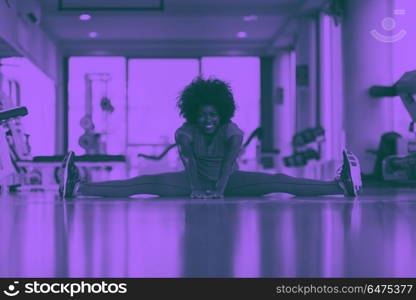 woman in a gym stretching and warming up before workout. happy young african american woman in a gym stretching and warming up before workout duo tone filter