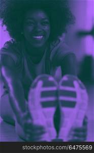 woman in a gym stretching and warming up before workout. happy young african american woman in a gym stretching and warming up before workout duo tone filter