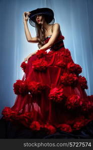 Woman in a hat and red dress on blue background