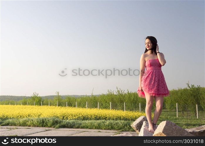 Woman in a pink dress at sunset. Beautiful brunette woman with pink dress enjoys the sunset light near an orchard in Moravia, Czech Republic
