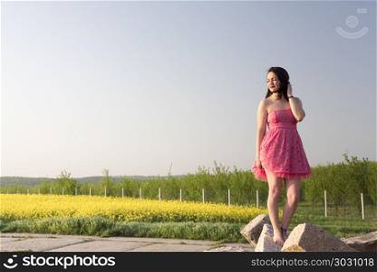 Woman in a pink dress at sunset. Beautiful brunette woman with pink dress enjoys the sunset light near an orchard in Moravia, Czech Republic