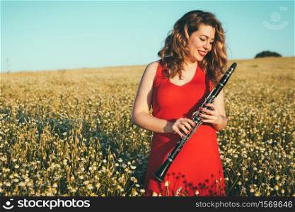 woman in a red dress in the field playing the clarinet