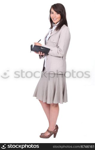 Woman in a skirt suit writing in a personal organizer