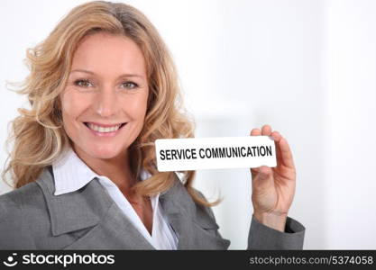 "Woman in a suit holding a Service Communication" sign""