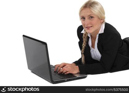 woman in a suit lying and working on her laptop