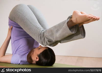 Woman in a traditional stretching yoga pose at home or gym