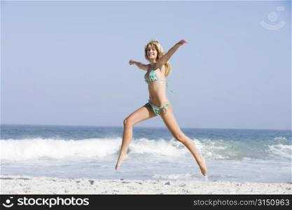 Woman in a two piece bathing suit running on a beach