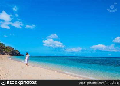 Woman in a white dress on beach. Woman in a white dress is walking on the blue sea beach background