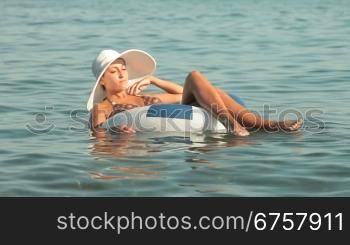 woman in a white hat floating on the innertube