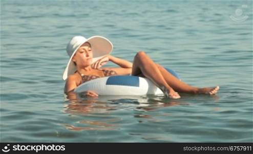 woman in a white hat floating on the innertube