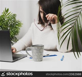 woman in a white sweater sits at a table and works at a computer. Remote work, freelance. Online shopping