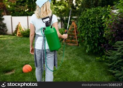Woman in apron watering flowers in the garden. Female gardener takes care of plants outdoor, gardening hobby, florist lifestyle and leisure. Woman in apron watering flowers in the garden