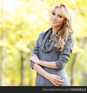 Woman in autumn forest. Portrait of a beautiful blond smiling woman in autumn forest