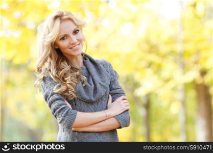 Woman in autumn forest. Portrait of a beautiful blond smiling woman in autumn forest