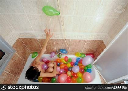 Woman in bath full of balloons