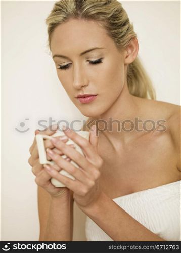 woman in bath robe holding mug of tea
