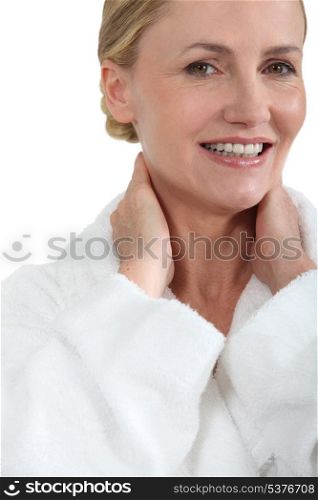 Woman in bath robe smiling with hands behind neck