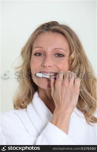 Woman in bathrobe cleaning teeth