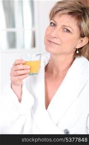Woman in bathrobe drinking orange juice