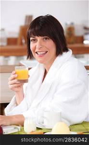 woman in bathrobe having orange juice