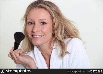 Woman in bathrobe holding make-up brush