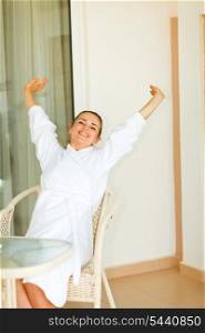 Woman in bathrobe stretching on terrace