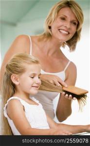 Woman in bathroom brushing young girl&acute;s hair
