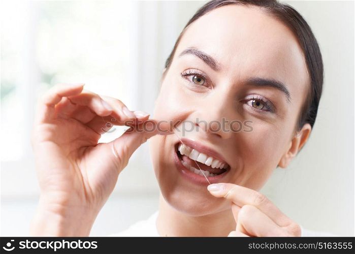 Woman In Bathroom Flossing White Teeth