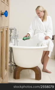 Woman in bathroom putting bubble bath in bathtub