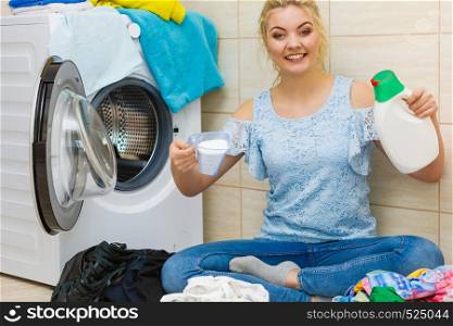 Woman in bathroom with dirty clothes doing laundry, choosing the best detergent. Female holding liquid gel bottle and powder container. Household duties.. Girl doing laundry choose best detergent.