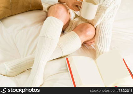 Woman in bed reading and relaxing with a cup of milk