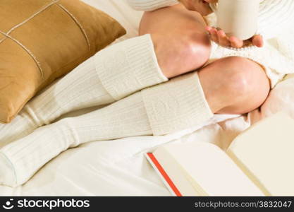 Woman in bed reading and relaxing with a cup of milk