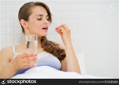 Woman in bed taking pills