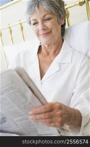 Woman in bedroom with newspaper smiling